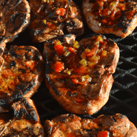 Grilled pork chops with salsa on grill.