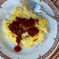 Scrambled eggs with red sauce on a plate.