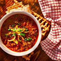 Bowl of chili with cheese and green onions.