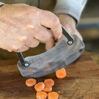 Hand using a knife to slice carrots.