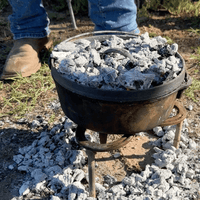 Cast iron pot on coals for cooking.
