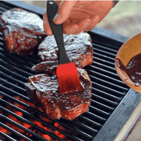 Grilling steaks with BBQ sauce and a brush.