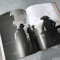 Open book with cowboys in silhouette.