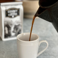 Coffee pouring into white mug.