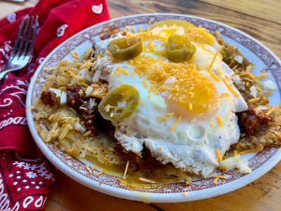 St. Louis Slinger with crispy hash browns, chili, fried eggs, shredded cheddar, diced onions, and pickled jalapeños.