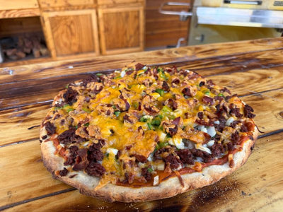 Bacon Jalapeno Cheeseburger Pizza on a wooden cutting board