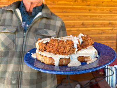 A blue plate with a chicken fried steak sandwich smothered in gravy on texas toast