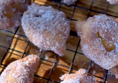 Funnel Cake Fried Peaches on a wire rack, dusted in sugar. 