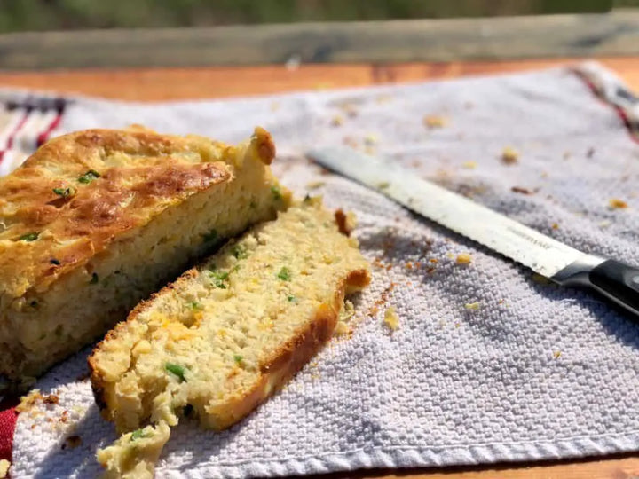Sliced cornbread with green onions on a towel.