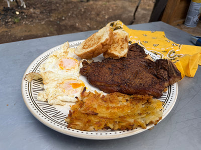 A white platter with steak and eggs, toast, fried eggs, and hashbrowns
