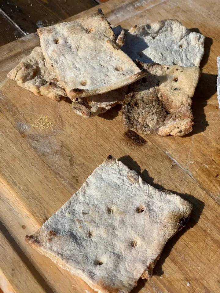 Stack of crispy flatbread on a wooden board.