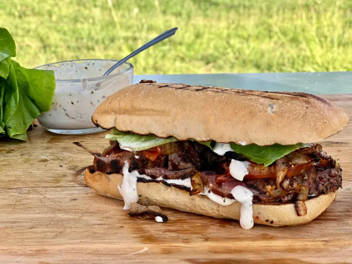 Grilled steak sandwich with sauce and lettuce.