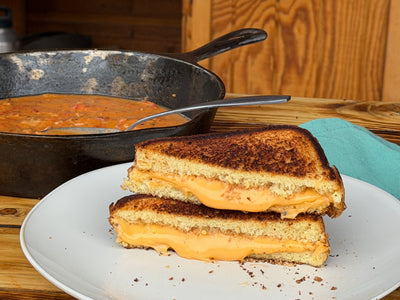 Gooey Grilled Cheese on a white plate with a cast iron skillet of tomato gravy behind it 