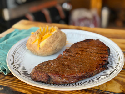 White plate with steak and baked potato on top 