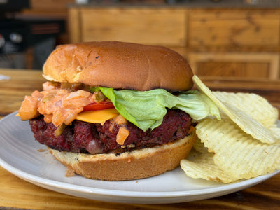 A cheeseburger with special sauce, lettuce on a hamburger bun, with potato chips