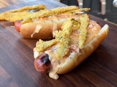 Hot dog with charred fried hatch chilies and a special sauce, grilled on a bun