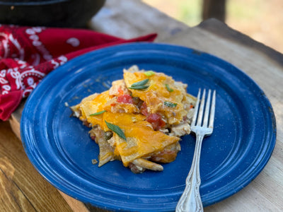 A blue plate with a serving of a chicken, cheese and tortilla chip casserole.