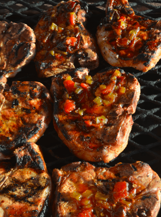 Grilled pork chops with salsa on grill.