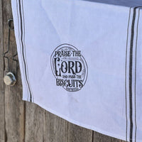 White tea towel with "Praise the Lord and pass the biscuits"