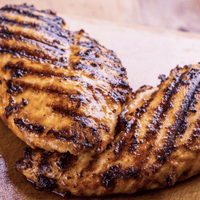 Grilled chicken breast on a cutting board.