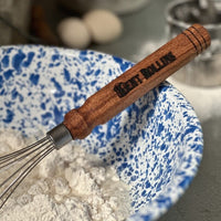 Wooden whisk in a mixing bowl of flour.