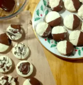 Chocolate-dipped cookies on a plate and parchment paper.