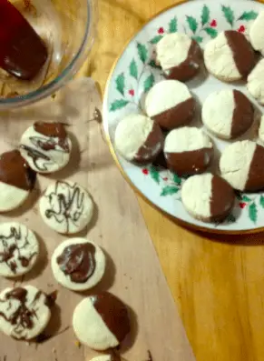 Chocolate-dipped cookies on a plate and parchment paper.