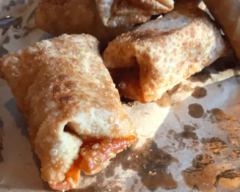 Fried egg rolls on a brown paper plate.