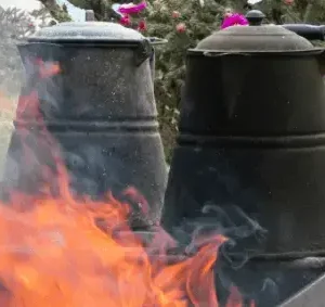 A fire is burning in the background of two pots.