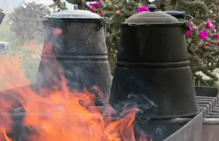 A fire is burning in the background of two pots.