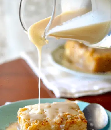 Creamy sauce being poured over cake.