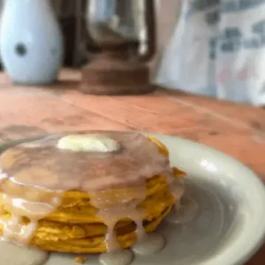 Stack of glazed pumpkin pancakes on a plate.