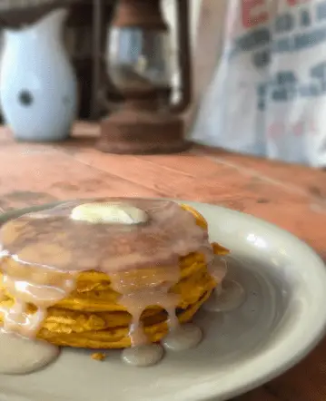 Stack of glazed pumpkin pancakes on a plate.