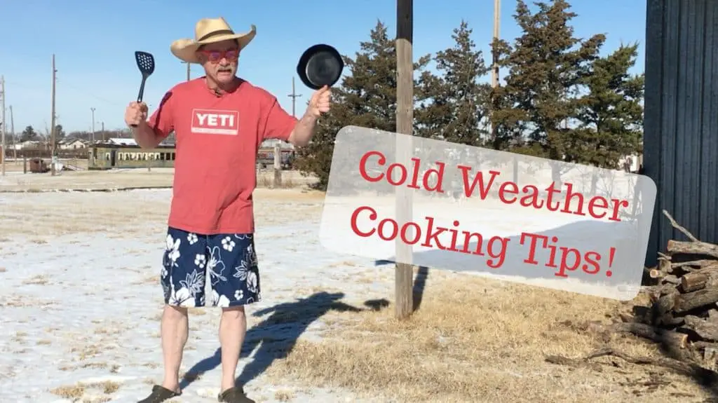 Man in shorts cooking outdoors in the snow.