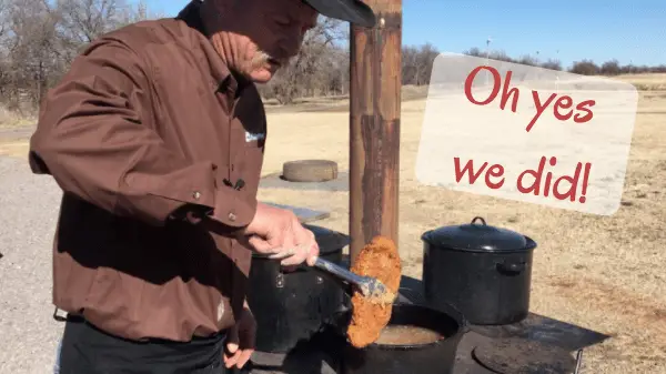 Man cooking food outdoors with a sign.