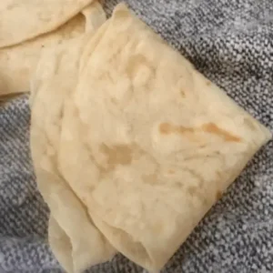 Folded flatbread on a gray fabric.