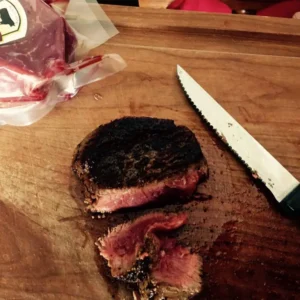 Seared steak on a wooden cutting board.