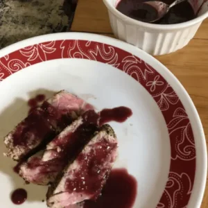 Grilled meat with red wine sauce on a plate.