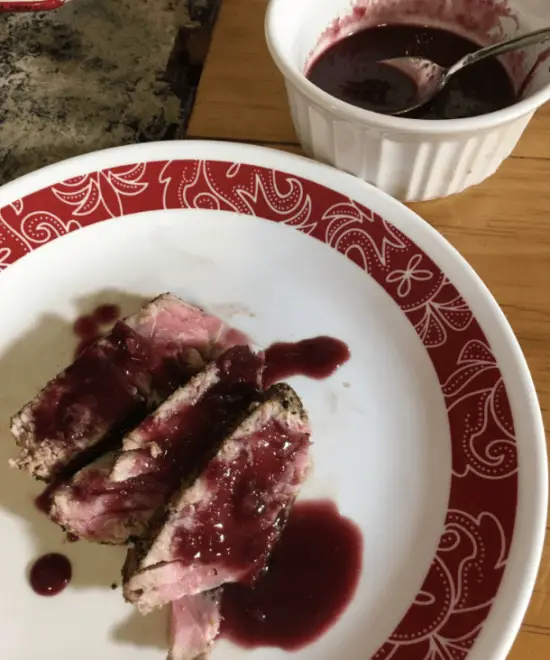 Grilled meat with red wine sauce on a plate.