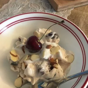 Ice cream with cherry and almonds in bowl.