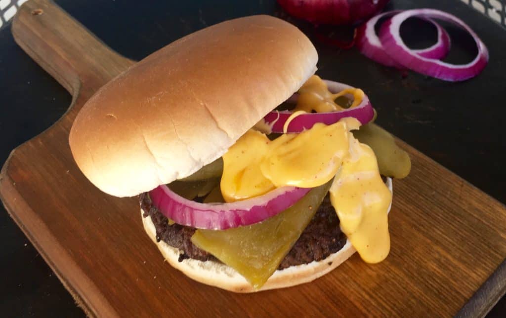 Cheeseburger with onion and pickles on bun.