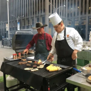 Two men grilling food on a city street.