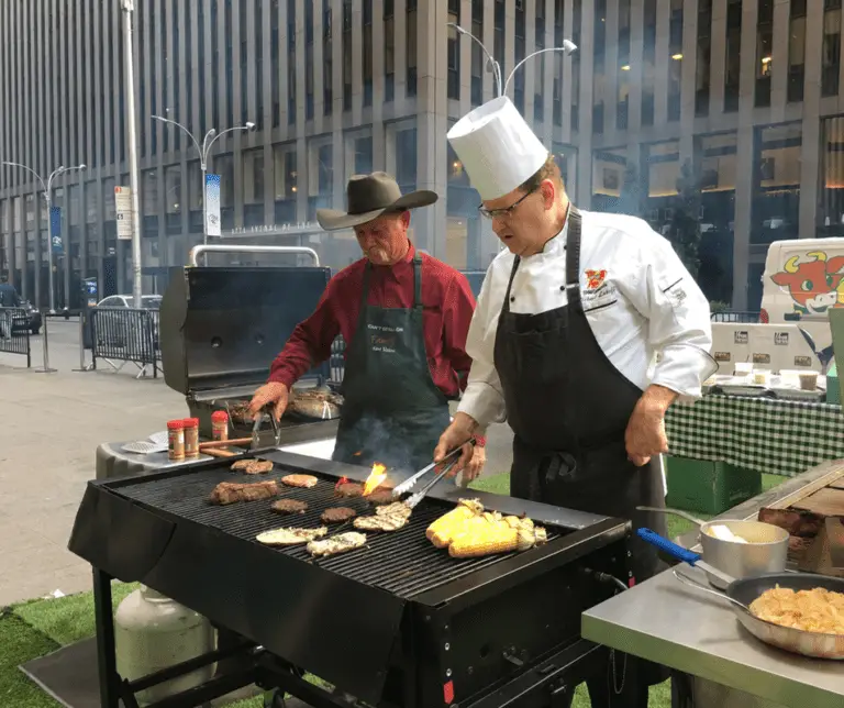 Two men grilling food on a city street.