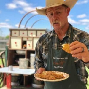 Man in a cowboy hat holding a cookie.