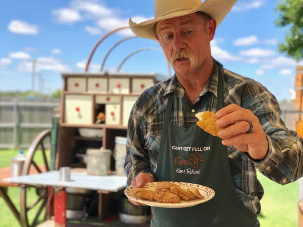 Man in a cowboy hat holding a cookie.