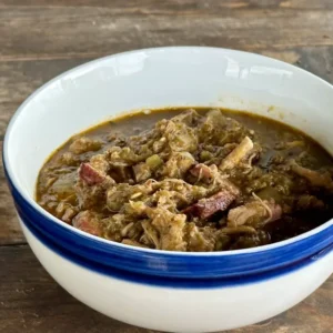 Bowl of stew with meat and greens.