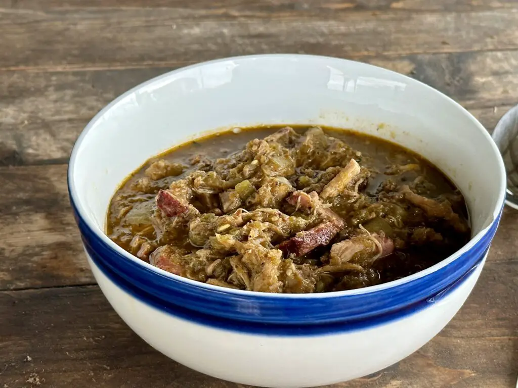 Bowl of stew with meat and greens.