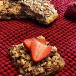 Nutty dessert bar with strawberries on red cloth.