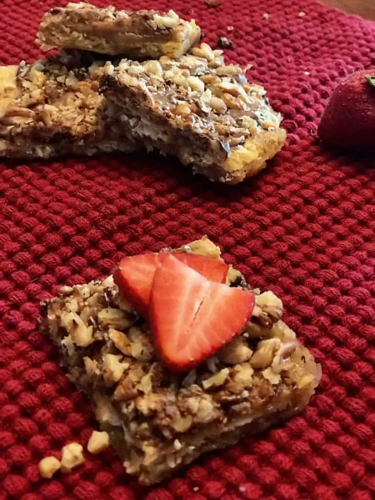 Nutty dessert bar with strawberries on red cloth.