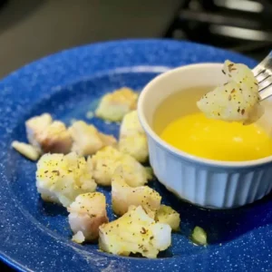 Fish dipped in yellow sauce on a blue plate.